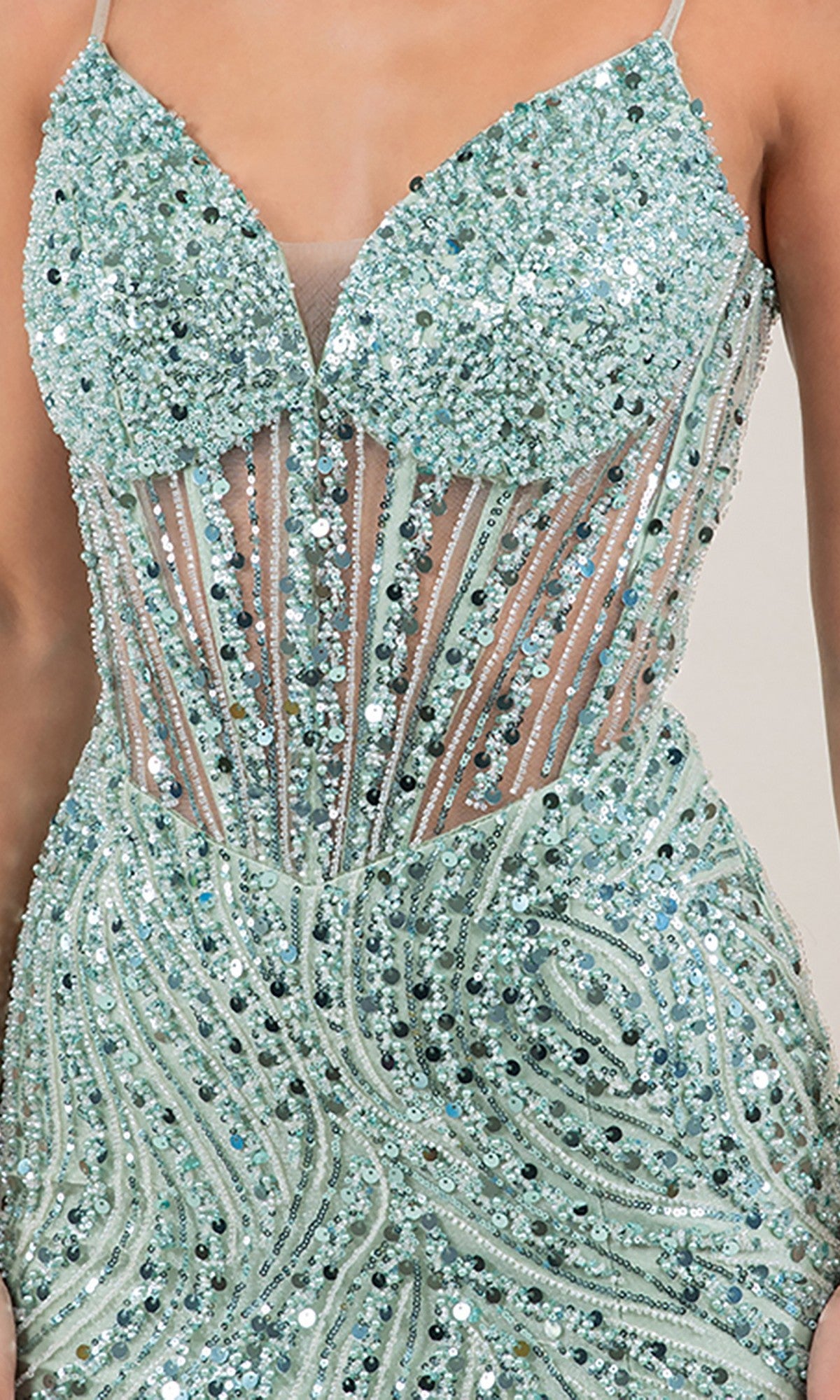 Close-up of a person wearing the Long Prom Dress: Cinderella Couture 8329J, featuring a sparkly light blue-green color, sequin-embellished bodice, thin straps, and sheer panel detailing.